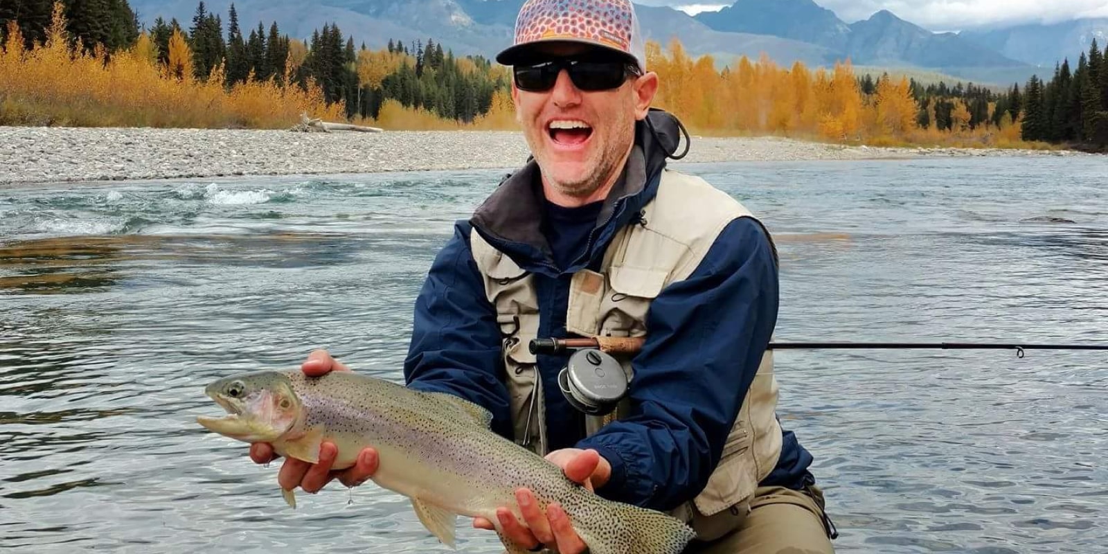 Man smiling with his fly fishing trout catch on the Flathead River